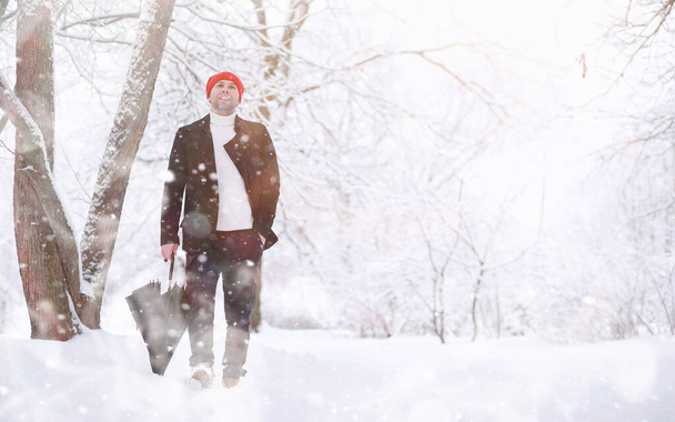 Muž na procházce v parku. Mladý muž s deštníkem pod zimním sněhem. - Fotografie, Obrázek