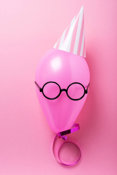 Party concept with pink ballon, party hat and looking glass. Top down view in pink background - Fotoğraf, Görsel