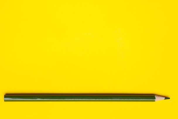 horizontal dark green sharp wooden pencil on a bright yellow background, isolated, copy space, mock up - Φωτογραφία, εικόνα