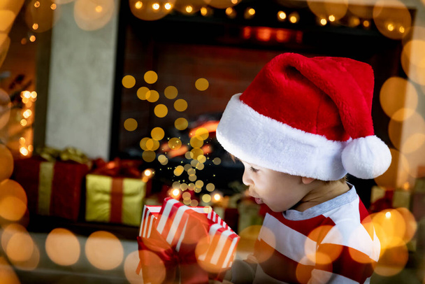 Surprised child opening Christmas gift. Funny kid at home. Xmas holiday concept - Fotoğraf, Görsel