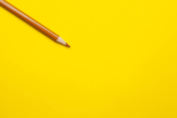 diagonal light brown sharp wooden pencil on a bright yellow background, isolated, copy space, mock up - 写真・画像