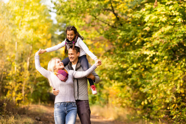 Familia feliz divirtiéndose al aire libre en el parque de otoño contra las hojas borrosas fondo - Foto, imagen