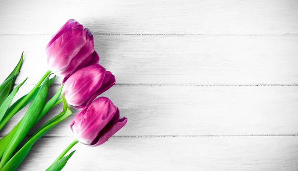 Три фіолетові тюльпани на сірому столі
. - Фото, зображення