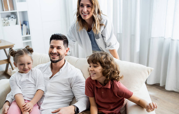 Kids sitting on sofa with cheerful parents - Photo, Image