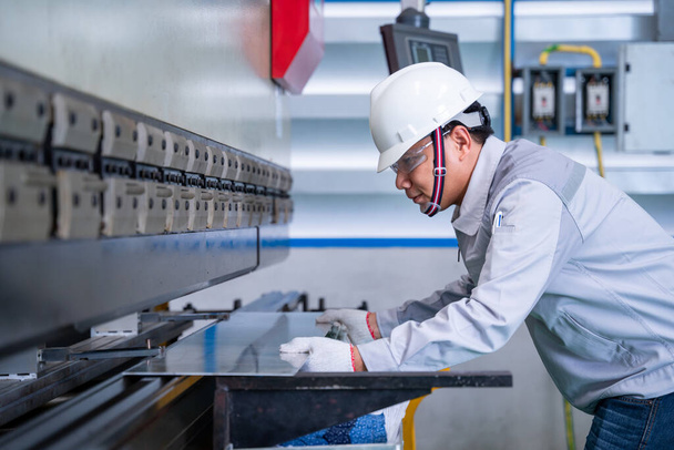 Азиатский технический работник носить защитный костюм и листовой металл изгиб на промышленном заводе, безопасность в первую очередь концепции. - Фото, изображение