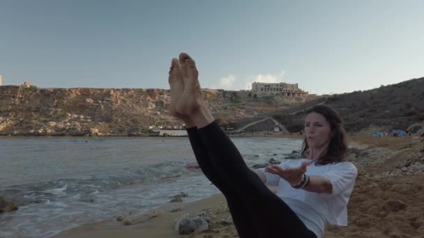 Frau um die 40 praktiziert am frühen Morgen Yoga am Sandstrand - Filmmaterial, Video