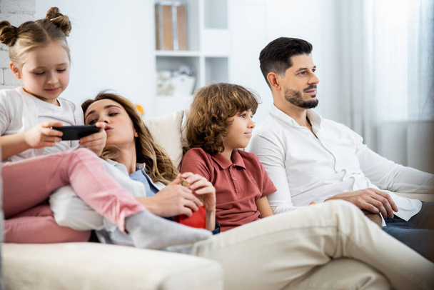 Family with kids sitting on sofa - Foto, imagen