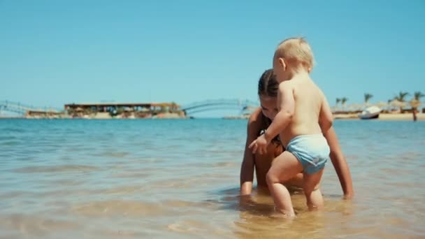 若い女性と楽しいです小さな男の子で暖かい水の中で海岸で晴れた日に. - 映像、動画