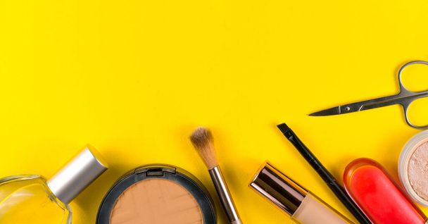 Vari cosmetici trucco decorativo su sfondo giallo. Diversi elementi essenziali di bellezza per le donne. - Foto, immagini
