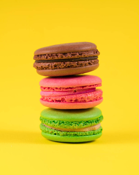 three colored macaroon on a yellow background - Photo, Image
