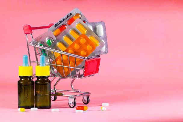 pastillas en un cochecito sobre un fondo rosa - Foto, Imagen
