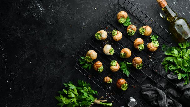 French food. Baked snails with pesto sauce on a black stone background. Top view. Free space for your text. - Фото, зображення