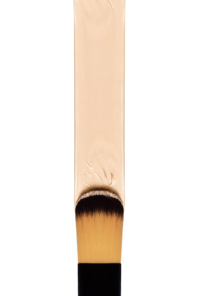 Cartel de concepto de arte de cosmetología del cepillo de maquillaje en primer plano, aplicando una base líquida sobre el fondo de la superficie blanca. Belleza, cuidado de la piel y maquillaje concepto de perfección de la piel - Foto, Imagen