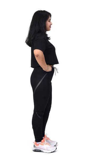  side view of a latin woman with sportswear looking at side on white background, hands on hip - Foto, Imagem