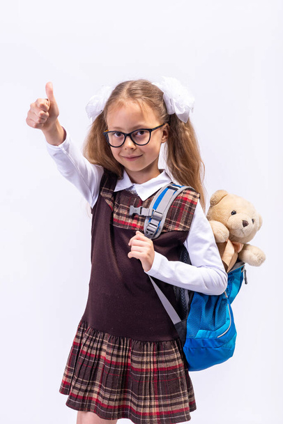 A little girl in a school uniform and with a backpack on her back. School concept. - Valokuva, kuva