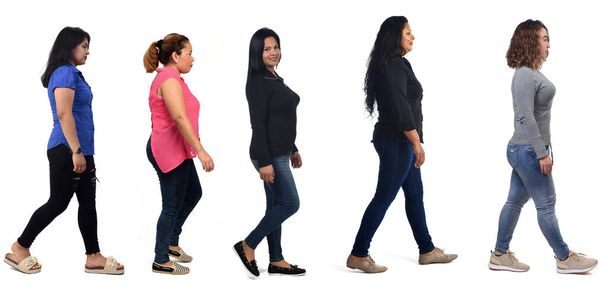 vista lateral de un grupo de mujeres latinoamericanas caminando sobre fondo blanco - Foto, Imagen