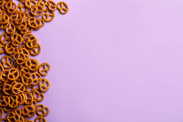 Delicious pretzel crackers on violet background, flat lay. Space for text - Photo, Image