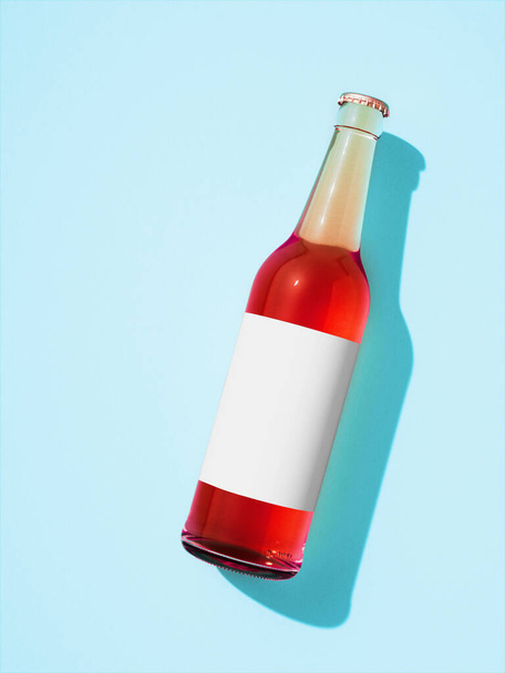 Botella de vidrio transparente sobre fondo azul claro. Colocación plana de botella de cerveza con etiqueta blanca en blanco y líquido rojo en el interior, sombra en el fondo. concepto de botella de bebida retro. - Foto, imagen