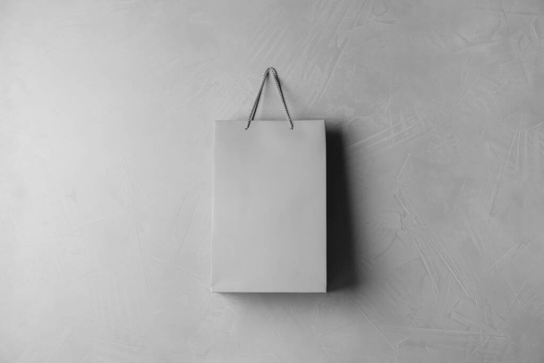Paper shopping bag hanging on grey wall - 写真・画像