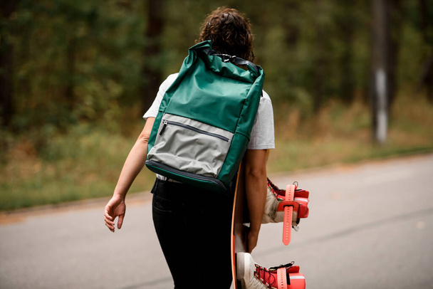 rear view of young woman with backpack on shoulders and wakeboard in hand - Foto, Bild