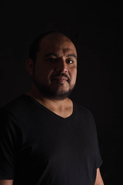 retrato de vista lateral oscura de un hombre latinoamericano sobre fondo negro - Foto, imagen