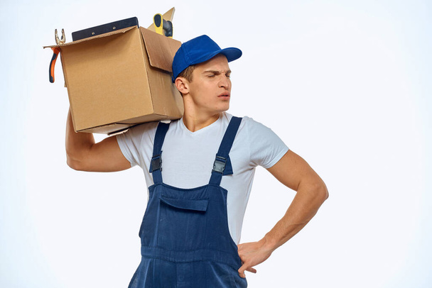 Un hombre en uniforme de trabajo con una caja en la mano cargando un servicio de entrega - Foto, imagen
