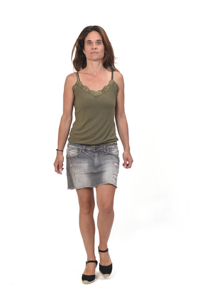 vista frontal do retrato completo de uma mulher em uma saia jeans andando sobre fundo branco,  - Foto, Imagem