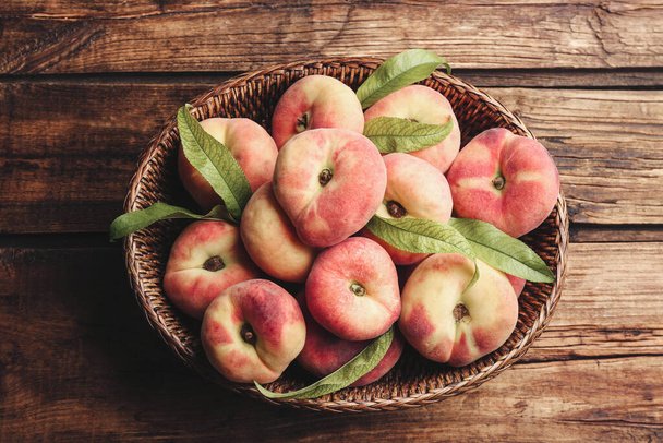 Fresh ripe donut peaches in basket on wooden table, top view - Foto, Imagen