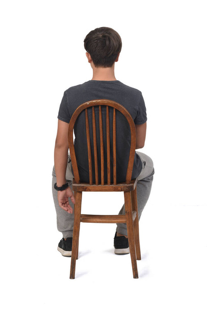 vue arrière d'un adolescent assis sur une chaise avec un fond blanc, - Photo, image