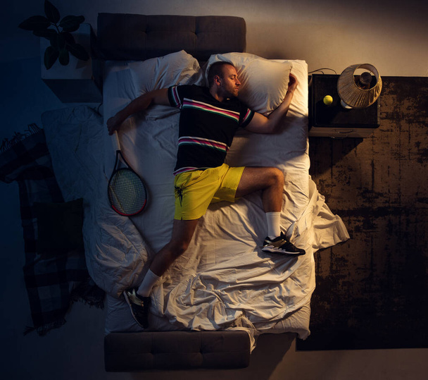Top view of young professional tennis player sleeping at his bedroom in sportwear with racket - Фото, зображення