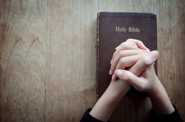 Beten Sie am Morgen, Frau betet mit den Händen zusammen, Frau betet, während sie die Bibel in der Hand hält Und einige der verschwommenen Bibeltexte - Foto, Bild