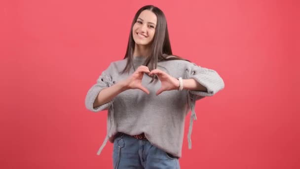 Happy woman put make with fingers heart shape, isolated over red background. - Footage, Video