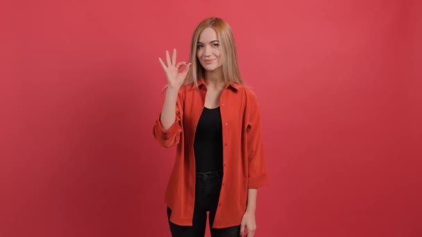 Fiatal nő mutatja rendben jel ujjak elszigetelt piros háttér. - Felvétel, videó