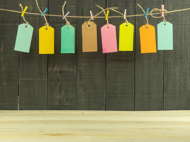 Eight price tags in different colors with space for text. Tags and inscriptions for text on a wooden background. The labels are hung on a rope with multi-colored clothespins - Фото, изображение