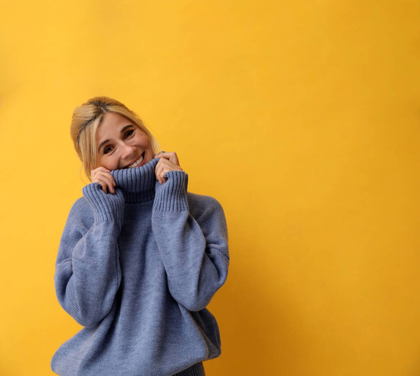 Happy woman in stylish sweater on yellow background. Space for text - Fotografie, Obrázek
