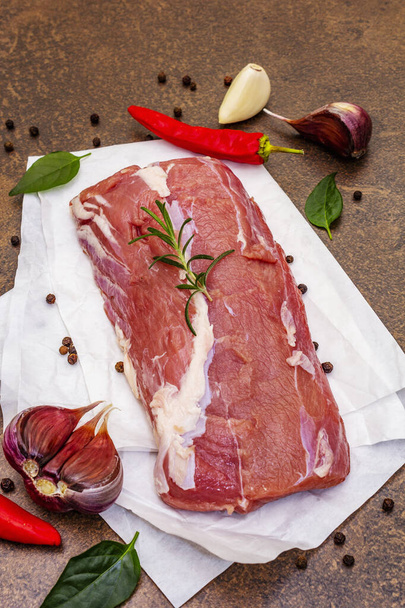 Raw veal meat. Fresh piece with ripe vegetables and fragrant spices. Stone concrete background, close up - Photo, Image