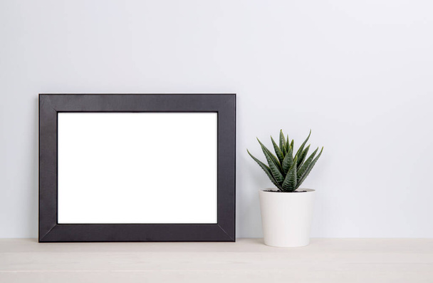 Mockup frame and plants in pot on table top at home, mock up poster for presentation on desk, indoor, your design for gallery photo and picture, border template and decoration for advertising. - Photo, Image