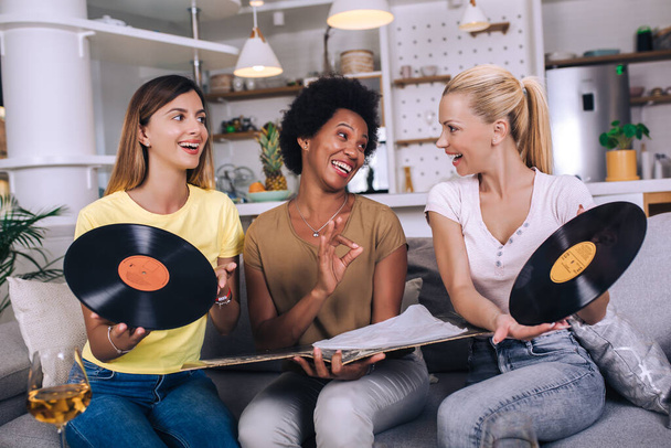 Happy young female friends at home listening vinyl at home. Choosing next record. - Foto, Imagem