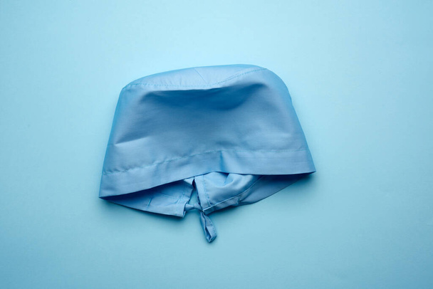 casquette médicale textile bleue avec liens pour médecin, chirurgien sur fond bleu, vue de dessus - Photo, image