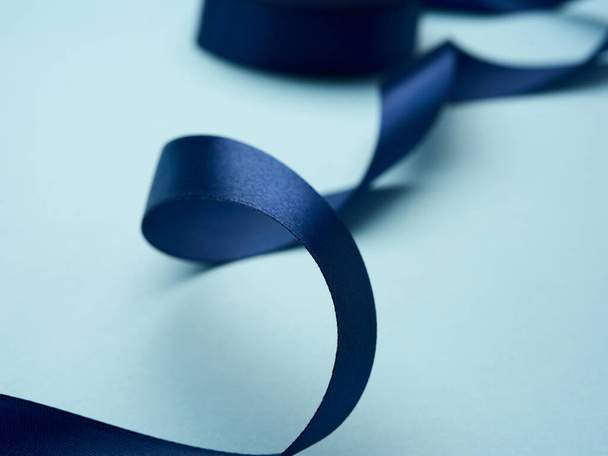 curled dark blue silk ribbon on light blue background, close up - Φωτογραφία, εικόνα