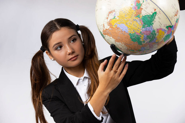 Portrait of caucasian woman holding a globe model, looks to it. Isolated white background - Foto, Imagem