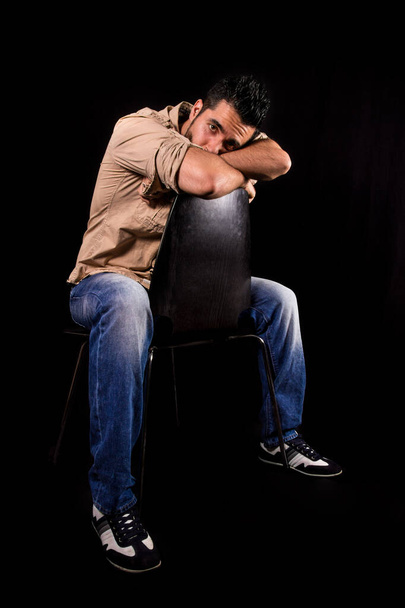 Człowiek zmartwiony i troskliwy, siedzący tyłem na krześle z głową i ramionami opartymi na oparciu - Zdjęcie, obraz