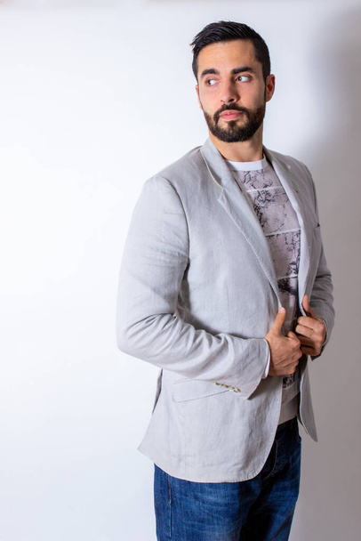 Handsome man with jacket, t-shirt and jeans, looking back on white background - Foto, afbeelding