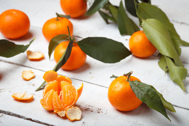 mandarins with leaves on white woodwn background. - 写真・画像