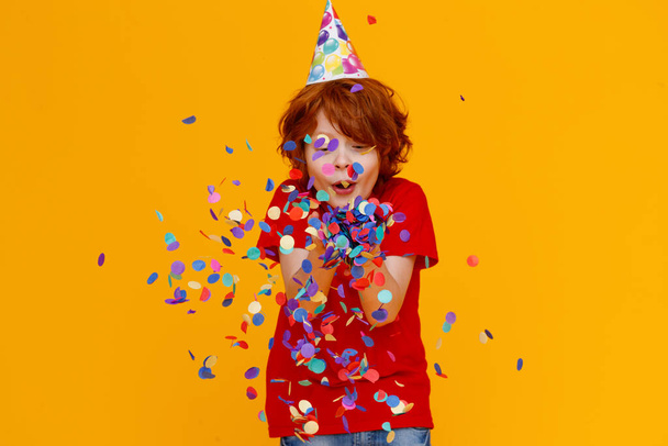 happy birthday! ginger child boy with confetti on  colored yellow backgroun - Foto, imagen