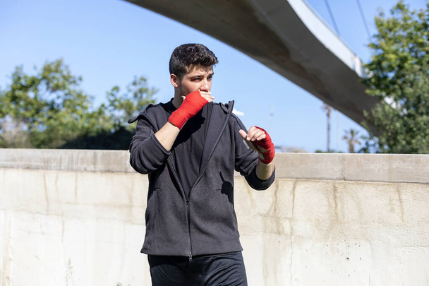 Young sports fitness man outdoors in park make boxing exercises. - Fotó, kép