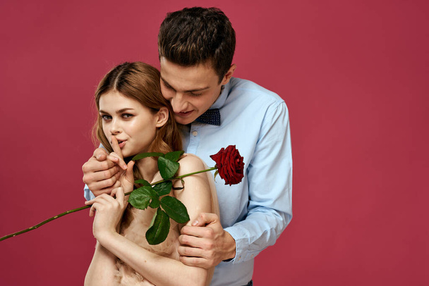 innamorato uomo e donna con un fiore rosso su uno sfondo rosa si abbracciano Copia Spazio - Foto, immagini