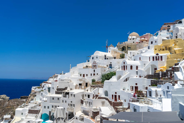 Vista panorâmica da cidade de Oia, na ilha de Santorini, com antigas casas caiadas de branco e moinho de vento tradicional, Grécia Paisagem grega em um dia ensolarado - Foto, Imagem
