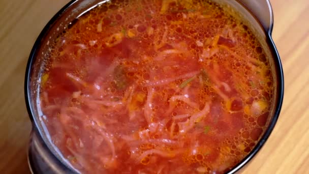 Ein Teller vom ersten Gang der Borschtsch-Suppe mit Tomaten, Kohl und Kartoffeln in Fleischbrühe steht auf dem Esstisch, Großaufnahme, Makro-Video - Filmmaterial, Video