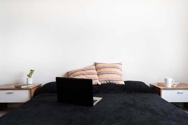 Schwarzer Laptop offen auf leerem Bett. Konzept von Telearbeit und Home-Office. - Foto, Bild